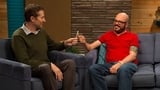 David Cross Wears a Red Polo Shirt & Brown Shoes with Red Laces